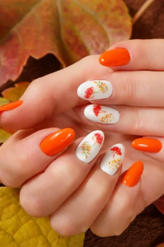 Long nails with hand-painted fall leaf designs in red, orange, and yellow tones.