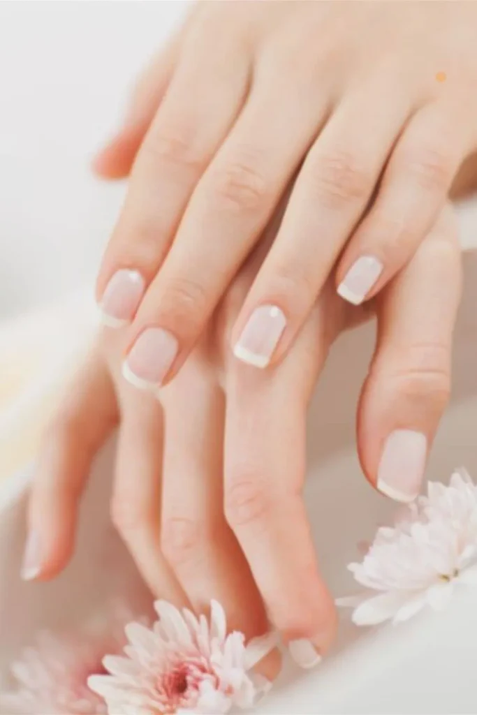 A close-up of a French manicure on healthy natural nails to show the final results of learning how to grow nails fast.