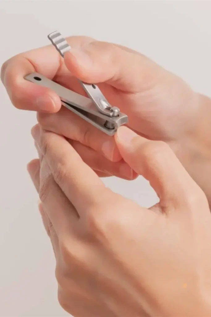 Close-up of metal nail clippers being used on natural nails to demonstrate grooming techniques for how to grow nails fast.