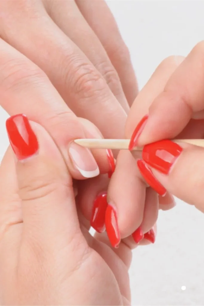 Gentle Cuticle Care Guide demonstrating the use of a wooden stick to push back cuticles on a French tip nail.