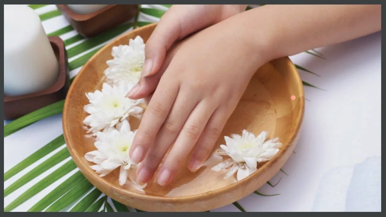 Gentle Cuticle Care Guide featured image showing hands soaking in a wooden bowl with white flowers for hydration.