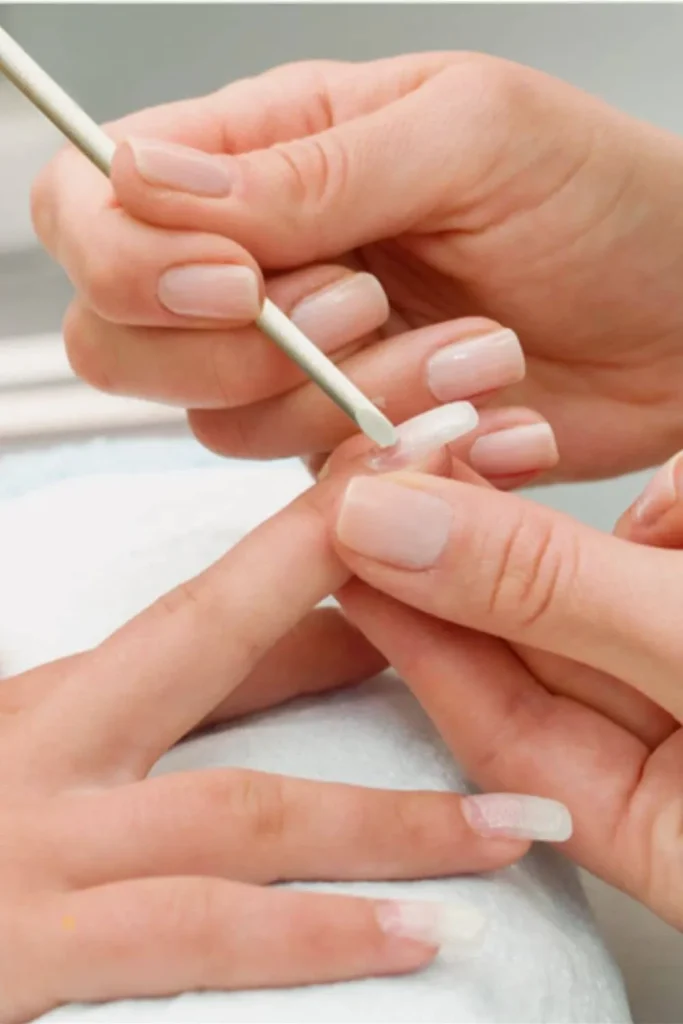 Gentle Cuticle Care Guide demonstrating the use of a wooden stick to gently push back cuticles for a clean manicure.